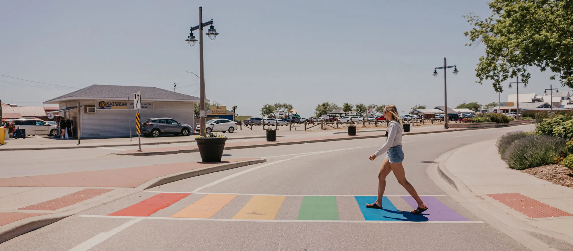 A rainbow crosswalk on William Street, with the main beach behind